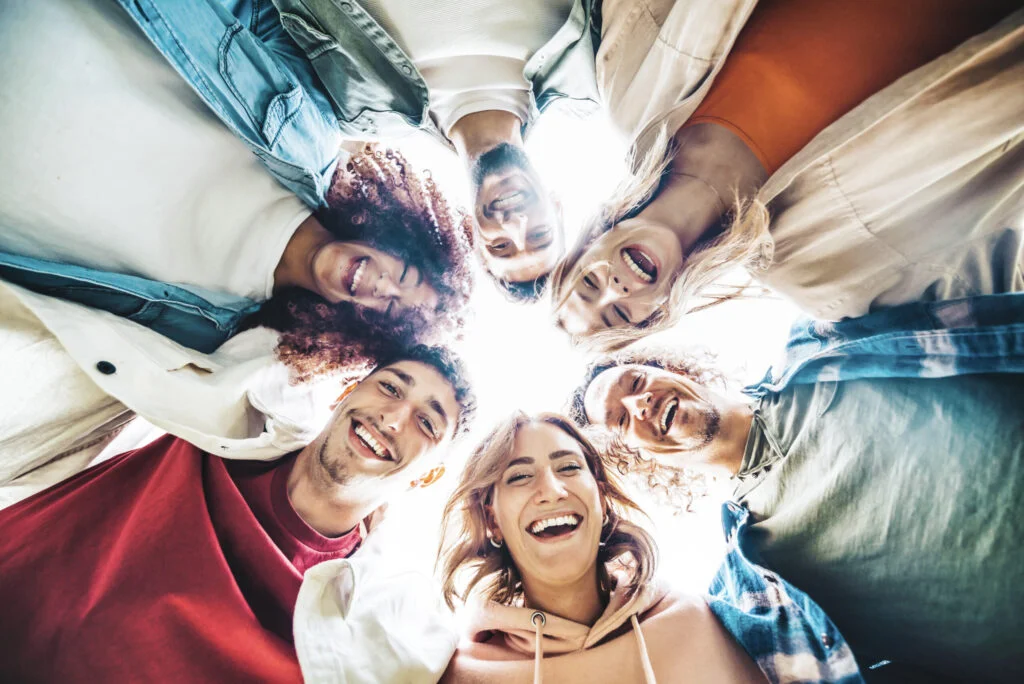 Happy group of friends hugging together in a circle - Multiracia Happy group of friends hugging together in a circle - Multiracia